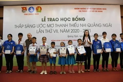 Đại diện Nhóm những người bạn Quảng Ngãi tại TP Hồ Chí Minh và lãnh đạo tỉnh Quảng Ngãi trao học bổng cho các em học sinh. (Ảnh: Đinh Hương/TTXVN)