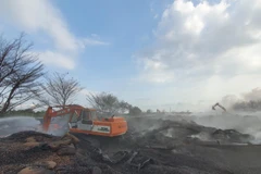 Hàng chục chiếc xe xúc đang cào lớp hạt điều đã cháy để lực lượng Phòng cháy chữa cháy và Cứu nạn, cứu hộ tiến hành làm mát kho hàng của Công ty cổ phần Thành Chí. (Ảnh: Huỳnh Ngọc Sơn/TTXVN)