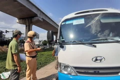 Lực lượng liên ngành kiểm tra phương tiện đưa rước nhân viên trên xa lộ Hà Nội. (Ảnh: Tiến Lực/TTXVN)