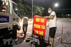 Lực lượng chức năng tháo gỡ biển hiệu phong tỏa. (Ảnh: Nguyên Lý/TTXVN)