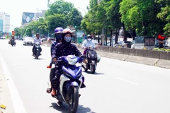 Người dân đều trang bị khẩu trang và mặc áo chống nắng kín khi di chuyển trên đường trong thời tiết nắng nóng. (Ảnh: Tá Chuyên/TTXVN)