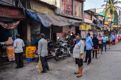 Người dân xếp hàng lấy sữa tại khu ổ chuột Dharavi ở Mumbai, Ấn Độ, ngày 6/4 vừa qua. (Ảnh: AFP/TTXVN)