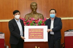 Chủ tịch Ủy ban Trung ương MTTQ Việt Nam Trần Thanh Mẫn trao tượng trưng kinh phí cho đại diện Bộ Y tế. (Ảnh: Doãn Tấn/TTXVN)