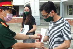Đại tá Nguyễn Hữu Nghĩa, Phó Chỉ huy trưởng Bộ Chỉ huy Quân sự tỉnh Quảng Nam trao quyết định hoàn thành nhiệm vụ cách ly y tế tập trung cho công dân. (Ảnh: Hữu Trung/TTXVN)