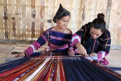 Chị Hồ Thị Viên (bên phải) cùng một nghệ nhân lớn tuổi hoàn thành sản phẩm thổ cẩm tại làng dệt Pơ Nang, xã Tú An, thị xã An Khê, tỉnh Gia Lai. (Ảnh: Hồng Điệp/TTXVN)