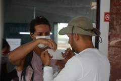 Hành khách nước ngoài đeo khẩu trang sau khi được các nhân viên tại Ga Đà Nẵng nhắc nhở. (Ảnh: Văn Dũng/TTXVN)