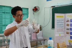 Em Trịnh Hoàng Long pha chế ngâm hóa chất với xương cá ngừ đã qua xử lý thô trong phòng thí nghiệm của trường THPT Nguyễn Văn Trỗi. (Ảnh: Phan Sáu/TTXVN)