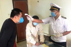 Các thuyền viên trên tàu được đo thân nhiệt, kiểm tra sức khỏe và khai báo y tế phòng tránh dịch bệnh COVID-19. (Ảnh: TTXVN phát)