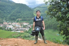 Nhà báo Đinh Hữu Dư trên đường tác nghiệp (Ảnh: Nội san TTXVN)