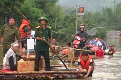 Các lực lượng chức năng dùng bè mảng giúp các gia đình có người chết đưa đi mai táng. (Ảnh: Vũ Hà/TTXVN)