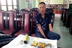 Một trong 2 đối tượng cùng tang vật bị bắt giữ. (Ảnh: Văn Đức/Vietnam+) 