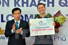 Bộ trưởng Bộ Văn hóa-Thể thao và Du lịch Nguyễn Ngọc Thiện tặng hoa, kỷ niệm chương cho ông Michael Tonge - du khách thứ 10 triệu đến Việt Nam trong năm 2016. (Nguồn: TTXVN)