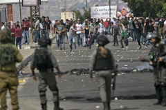 Người Palestine và các lực lượng Israel trong cuộc đụng độ tại Nablus ngày 15/5/2022. (Ảnh: AFP/ TTXVN)