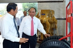 Thủ tướng Nguyễn Xuân Phúc xem các sản phẩm của Tập đoàn công nghiệp cao su Việt Nam. (Ảnh: Thống Nhất/TTXVN)