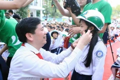 Tặng mũ bảo hiểm đạt chuẩn cho học sinh tiểu học. (Ảnh: Phạm Kiên/TTXVN)