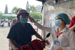 Đo thân nhiệt cho người dân đến khám bệnh tại Bệnh viện Thống Nhất Thành phố Hồ Chí Minh. (Ảnh: Đinh Hằng/TTXVN)