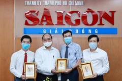 Chủ tịch nước Nguyễn Xuân Phúc tặng chân dung Chủ tịch Hồ Chí Minh cho Ban biên tập Báo Sài Gòn Giải phóng. (Ảnh: Thống Nhất/TTXVN)