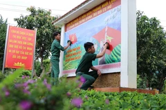 Các chiến sỹ Đồn Biên phòng Huổi Luông (Lai Châu) chỉnh trang lại bức cổ động bầu cử. (Ảnh: Nguyễn Oanh/TTXVN)