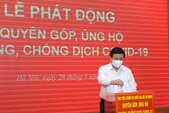Đồng chí Nguyễn Xuân Thắng, Ủy viên Bộ Chính trị, Giám đốc Học viện Chính trị quốc gia Hồ Chí Minh quyên góp ủng hộ Quỹ phòng, chống COVID-19. (Ảnh: Nguyễn Điệp/TTXVN)