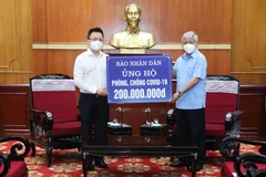 Chủ tịch Ủy ban Trung ương Mặt trận Tổ quốc Việt Nam Việt Nam Đỗ Văn Chiến tiếp nhận ủng hộ số tiền 200 triệu đồng từ ông Lê Quốc Minh, Ủy viên Trung ương Đảng, Tổng Biên tập Báo Nhân Dân. (Ảnh: Minh Đức/TTXVN)