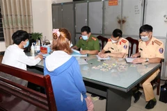Các lực lượng chức năng thuộc Công an tỉnh Hà Nam phát hiện, lập biên bản xử phạt người vi phạm không đeo khẩu trang nơi công cộng. (Ảnh: Đại Nghĩa/TTXVN)