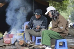 Người dân Hà Nội đốt củi sưởi ấm ngay trên vỉa hè. (Ảnh: Hà My/TTXVN phát)