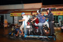 Xe ba gác máy vận chuyển xe máy của người dân qua điểm ngập sâu do triều cường tại TP.HCM. (Ảnh: Mạnh Linh/TTXVN)