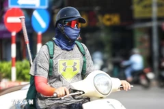 Người dân bịt kín khi ra đường trong ngày nắng nóng để đảm bảo sức khỏe. (Ảnh: TTXVN phát) 