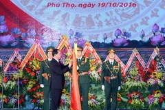 Chủ tịch nước Trần Đại Quang gắn Huân chương Quân công hạng Nhất lên lá cờ truyền thống của Quân khu 2. (Ảnh: Nhan Sáng/TTXVN)