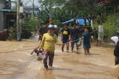Tại xã Phước Tân (TP. Biên Hòa), chính quyền địa phương phải căng dây để người dân bám víu khi đi qua vùng ngập lụt. (Ảnh: Sỹ Tuyên/TTXVN)