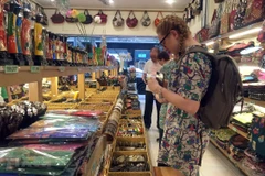 Khách nước ngoài lựa chọn sản phẩm lưu niệm thủ công mỹ nghệ. (Ảnh: Gia Thuận/TTXVN)