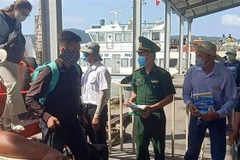 Đoàn viên thanh niên Bộ đội Biên phòng tỉnh phát khẩu trang miễn phí cho du khách từ huyện đảo Phú Quốc vào thành phố Rạch Giá bằng tàu biển. (Ảnh: Lê Sen/TTXVN)