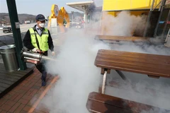 Nhân viên y tế phun thuốc khử trùng tại một trạm nghỉ trên đường cao tốc ở Chilgok, tỉnh Bắc Gyeongsang, Hàn Quốc, nhằm ngăn chặn sự lây lan của COVID-19. (Ảnh: Yonhap/TTXVN)