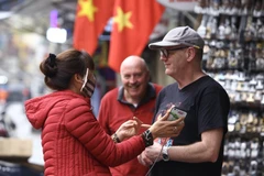 Du khách mua hàng hoá trên phố Hàng Ngang cũng không quan tâm đeo khẩu trang. (Ảnh: Minh Quyết/TTXVN)