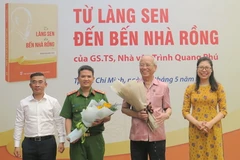 Giám đốc Nhà Xuất bản Chính trị Quốc gia Sự thật tại Thành phố Hồ Chí Minh Nguyễn Thị Quỳnh Nga tặng hoa cho Giáo sư, Tiến sỹ, Nhà văn Trình Quang Phú tại chương trình. (Nguồn: Trang tin điện tử Đảng bộ Thành phố Hồ Chí Minh)