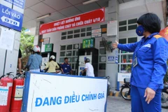 Nhân viên Petrolimex hướng dẫn khách hàng mua xăng trước khi điều chỉnh giá (Ảnh: Đức Duy/Vietnam+)