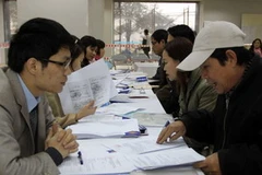 Cán bộ của Vinaconex Xuân Mai hướng dẫn người dân các thủ tục nộp hồ sơ mua nhà thu nhập thấp. (Ảnh: Tuấn Anh/TTXVN)