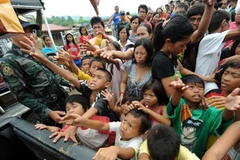 Người dân xếp hàng nhận lương thực cứu trợ từ các nhân viên chính phủ tại Iligan City trên đảo Mindanao ngày 19/12, hai ngày sau trận bão. (Ảnh: AFP/TTXVN)