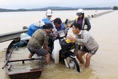 Trong mưa lũ xe máy không đi được, phương tiện đi lại của người dân là chiếc thuyền nhỏ. (Ảnh: Thanh Tùng/TTXVN)
