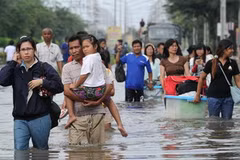 Người dân đi lại tại khu vực ngập lụt ở tỉnh Pathum Thani, ngoại ô Bangkok, ngày 18/10. (Ảnh: AFP/TTXVN)