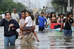 Người dân đi lại tại khu vực ngập lụt ở tỉnh Pathum Thani, ngoại ô Bangkok, ngày 18/10. (Ảnh: AFP/TTXVN)