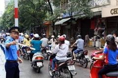 Thanh tra giao thông hướng dẫn người dân đi đúng làn đường trên tuyến phố Huế-Hàng Bài, Hà Nội. (Ảnh: Thế Duyệt/TTXVN)