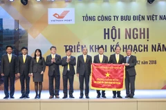 Thứ trưởng Bộ Thông tin và Truyền thông Nguyễn Thành Hưng (phải) thừa ủy quyền của Thủ tướng Chính phủ lên trao Cờ thi đua cho tập thể VietnamPost. (Nguồn: VNP) 