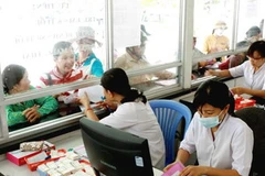Làm thủ tục cho người đến khám chữa bệnh có bảo hiểm y tế. (Ảnh: Dương Ngọc/TTXVN).