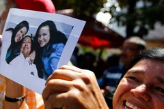 Người dân Venezuela vui mừng cầm bức ảnh Tổng thống Chavez và hai con gái. (Nguồn: Reuters)