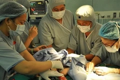 Các bác sỹ phẫu thuật tách rời cặp song sinh. (Ảnh: Phương Vy - TTXVN)