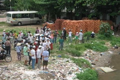 Hàng trăm người dân hiếu kỳ đã đổ về đoạn sông Bình Thủy xem vớt xác của nạn nhân. (Ảnh: Thanh Sang/Vietnam+)