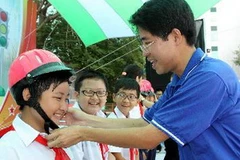 Tặng mũ bảo hiểm cho học sinh. (Ảnh: Thanh Vũ/TTXVN)