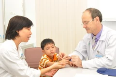 Bác sỹ Stephane Guerođang thăm khám cho trẻ bị dị tật bàn tay. (Ảnh: Minh Ánh/Vietnam+)