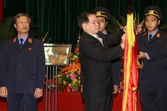 Chủ tịch nước gắn Huân chương Sao vàng lên lá cờ truyền thống của Viện Kiểm sát Nhân dân Tối cao. (Ảnh: Nguyễn Khang/TTXVN).